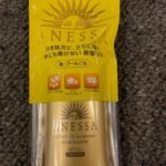 一瓶日本安耐晒（Anessa）防晒霜，金色瓶身，标注SPF50+及PA+++，放置在灰色地毯上