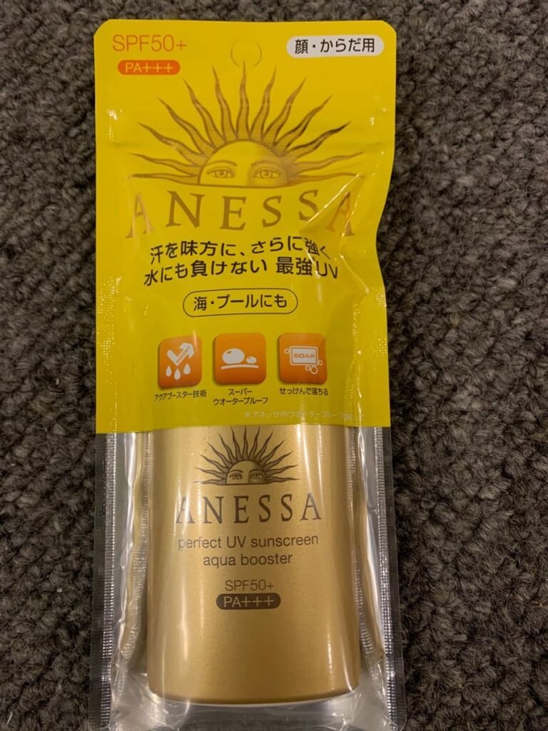 一瓶日本安耐晒（Anessa）防晒霜，金色瓶身，标注SPF50+及PA+++，放置在灰色地毯上